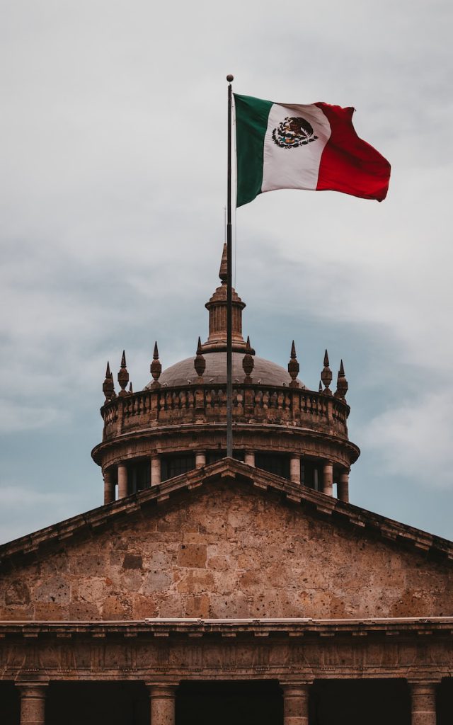 a mexican flag flying on top of a building